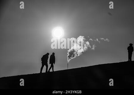 Réchauffement de la planète : un soleil et de la vapeur réchauffés s'élèvent alors que des silhouettes de personnes se trouvent sur une colline à Melbourne en Australie . Banque D'Images