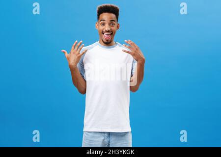 Un frère afro-américain heureux et enthousiaste en t-shirt avec une barbe qui secoue les paumes avec excitation et joie souriante gaiement exp Banque D'Images