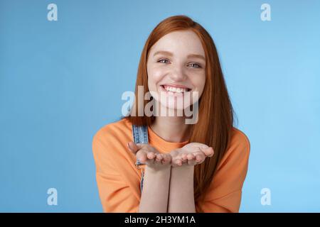 Mignon tendre gentille jeune fille de gingembre donnant tout l'amour vous, tenir quelque chose de palmiers montrant l'appareil photo sourire ravi présenter le présent Banque D'Images