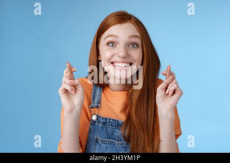 Excité émotionnel heureux gai heureux redhead fille sourire optimiste stare surprise ravie doigts de croix heureux croire rêve Banque D'Images