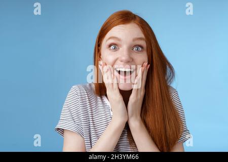 Joyeux rêve jeune enthousiaste redhead fan femelle à l'air fasciné appareil photo souriant admiration ravie visage tactile ravie Banque D'Images