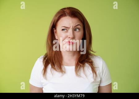 Perplexe doué incertain redhead femme smirking insatisfait frowning regarder de côté mécontent déçu hésitant pondering str Banque D'Images