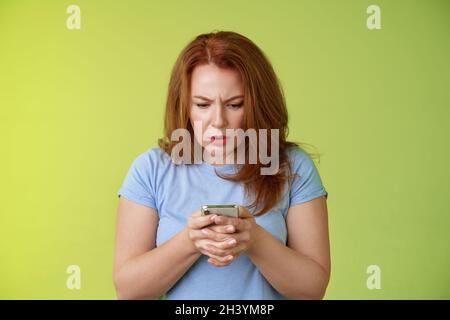 Méconnue et incertaine femme d'âge moyen Apprenez comment utiliser les médias sociaux essayer comprendre emoji semble intense concentré smartphone dis Banque D'Images