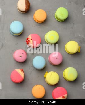 Macarons cuits aux saveurs différentes sur fond de ciment gris, vue du dessus Banque D'Images