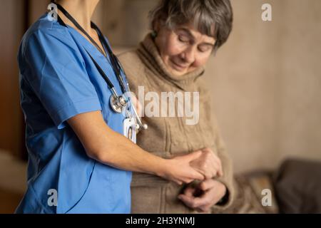 Une jeune infirmière fait preuve de soins et de professionnalisme par rapport à une femme âgée. Banque D'Images