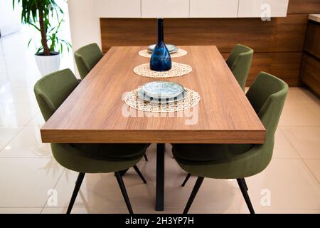 Cuisine moderne, coin intérieur, table à manger en bois de noyer et chaises vertes Banque D'Images