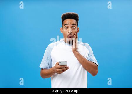 Prise de vue à la taille de charmed intrigué beau et élégant homme à la peau sombre avec des lèvres pliantes de coupe de cheveux afro dans wow ou extraordinaire expressio Banque D'Images