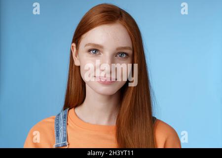 Jeune fille à tête rouge sortant yeux bleus portant un t-shirt orange combinaisons souriant agréablement décontracté parlant debout bonne humeur joie Banque D'Images