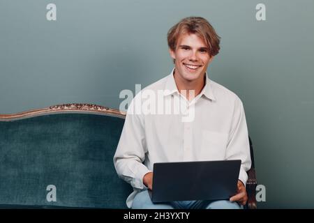 Portrait d'un jeune homme assis avec un ordinateur portable au studio. Banque D'Images