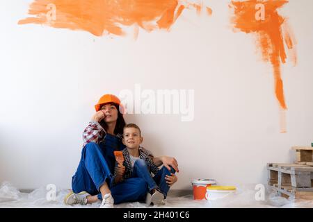 La mère et le fils réfléchis rêvent du projet d'un nouvel appartement ou d'une nouvelle maison.Famille effectuant des réparations à domicile.Peinture intérieure des murs Banque D'Images