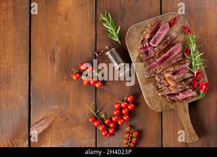 Morceau de bœuf rôti coupé en morceaux sur une planche à découper brun vintage, rare donaité.Délicieux steak, Banque D'Images