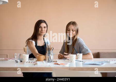 Vue de face de quatre belles femmes caucasiennes à l'atelier d'art. Un jeune enseignant enseigne le dessin Banque D'Images