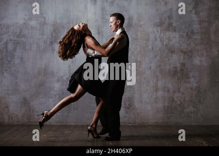 Homme et femme en robe noire danse tango en studio Banque D'Images