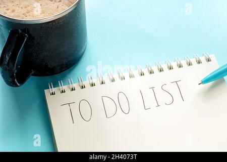 Liste des tâches, manuscrite dans un bloc-notes, avec une tasse de café et un stylo bleu Banque D'Images