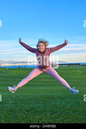 Bonne fille golfeur saut dans l'air avec les bras levés et club de golf en main après coup réussi. Banque D'Images