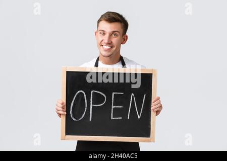 Concept des propriétaires de petites entreprises de vente au détail, des employés de cafés et de restaurants.Un serveur souriant et amical, un barista montrant que nous sommes ouverts, Banque D'Images