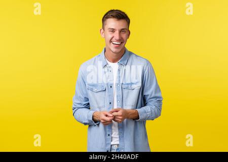 Beau garçon heureux étudiant dans une tenue décontractée, rire et sourire, ayant une conversation animée.Homme regardant joyeusement appareil photo, sta Banque D'Images