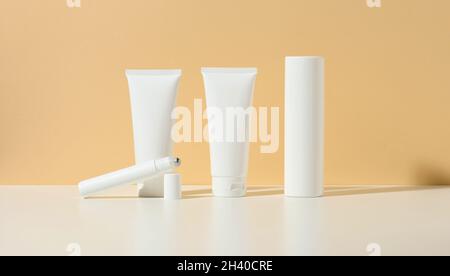 Vider tube en plastique blanc, rouleau fin, bouteille sur fond beige.Produits cosmétiques pour le gel de marque, la crème, la lotion, le shampooing. Banque D'Images