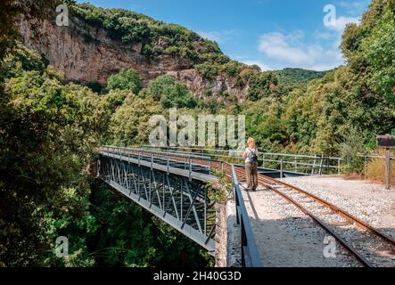 Vue arrière d'une femme blanche blonde qui se trouve dans le pont historique de Taxiarchis (alias de Chirico), près de la gare de Milies, au Mont Pélion, en Grèce. Banque D'Images