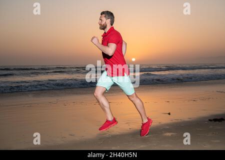 homme sportif coureur courant sur la plage d'été coucher de soleil, athlète Banque D'Images
