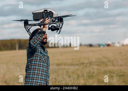 Homme pilote tenant DJI inspire 2 quadcopter drone dans les mains à l'extérieur du champ. Banque D'Images