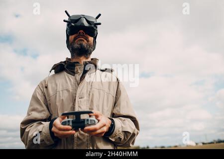 Homme contrôlant le drone quadricoptère fpv avec télécommande d'antenne de lunettes de protection Banque D'Images