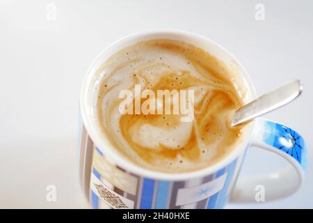 Bonjour !Tasse de café bleue sur fond clair.Café avec mousse sous la forme d'une source fraîche avec un sourire, vue du dessus horizontalement.Copier l'espace Banque D'Images