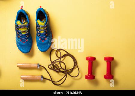 Équipement de fitness.Chaussures de sport sur un tapis de fitness.Faites du fitness avec des haltères et des cordes à sauter.Vue de dessus. Banque D'Images