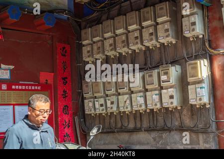 Un résident passe devant les compteurs électriques de chaque famille à l'entrée d'une cour dans le centre de Beijing, en Chine.31 octobre 2021 Banque D'Images