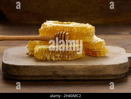 Cirer le nid d'abeille avec le miel sur un tableau noir et une cuillère en bois, table brune Banque D'Images