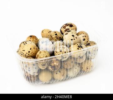 Un bouquet d'oeufs de caille crus dans un récipient en plastique transparent sur un fond blanc, nourriture de régime Banque D'Images