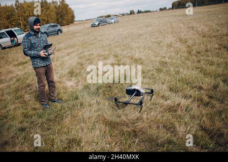 Man Pilot contrôle un drone quadricoptère avec pavé de commande à distance Banque D'Images