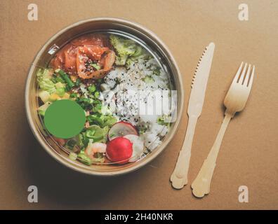 Salade saine avec saumon dans un emballage écologique de papier artisanal avec couverts en bois.Livraison de nourriture sans plastique.Vue de dessus. Banque D'Images