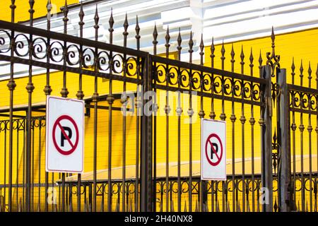 Pas de panneau de stationnement sur une clôture en métal noir en fer forgé contre un mur en brique jaune.Territoire privé extérieur, propriété, protection de la maison.Fonte décorative i Banque D'Images