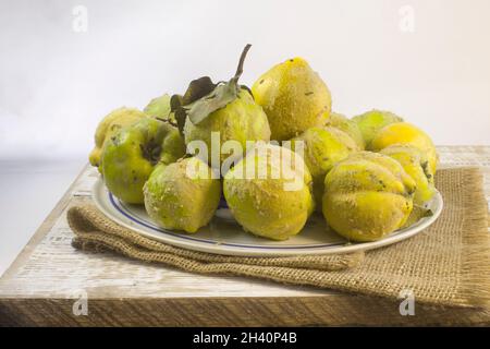 Coing biologique mûr frais avec feuilles sur table en bois gris et linge rugueux Vinrage encore la vie gros plan Banque D'Images