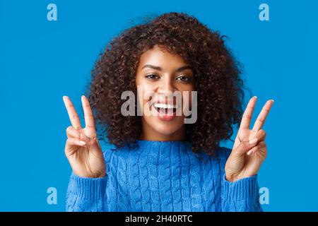Charismatique excitée et heureuse, souriante et joyeuse femme africaine américaine envoyant des vibes positifs, montrant le geste de paix et grinnin Banque D'Images