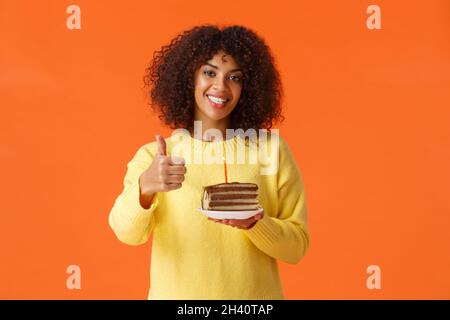 Gaie et optimiste afro-américaine petite fille de jour ayant une fête d'anniversaire, soufflez la bougie, tenant la plaque avec un délicieux gâteau, showi Banque D'Images