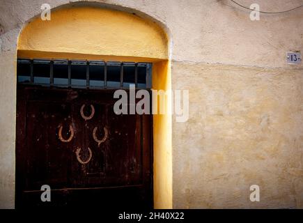 Quatre fers à cheval suréchantillés sur une grande porte d'entrée en Italie qui vient d'être le numéro treize.Chanceux ou malchanceux. Banque D'Images