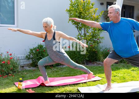 Joyeux couple caucasien expérimenté pratiquant le yoga ensemble dans le jardin Banque D'Images