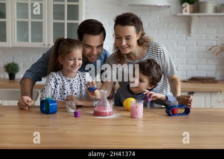 De jeunes parents heureux faisant des expériences chimiques avec de petits enfants. Banque D'Images