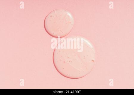 Gouttes de gel cosmétique sur fond rose.Des échantillons ronds de produits de beauté à la texture parée et aux bulles Banque D'Images
