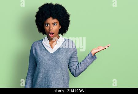 Jeune afro-américaine se présentant avec la paume ouverte dans le visage de choc, regardant sceptique et sarcastique, surpris par la bouche ouverte Banque D'Images