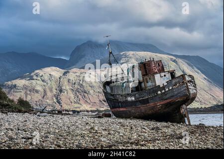 Bateau de pêche abandonné à Corpach sur la plage du Loch Linnhe à fort William dans les Highlands écossais vu ici avec Ben Nevis dans la distance Banque D'Images