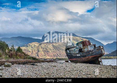 Bateau de pêche abandonné à Corpach sur la plage du Loch Linnhe à fort William dans les Highlands écossais vu ici avec Ben Nevis dans la distance Banque D'Images