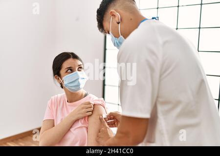 Jeune infirmière homme mettant l'aide de bande sur le bras de la femme à la clinique. Banque D'Images