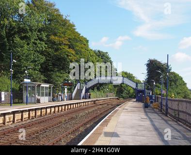 Vue sur le bâtiment de la gare ferroviaire à l'arrière près de grange au-dessus des sables à cumbria Banque D'Images