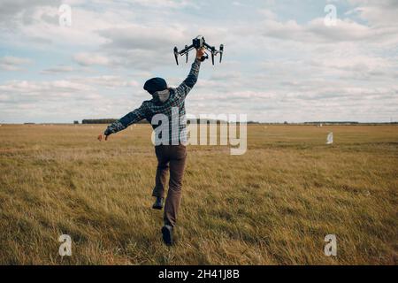 Homme pilote tenant un drone quadcopter dans les mains à l'extérieur du champ. Banque D'Images