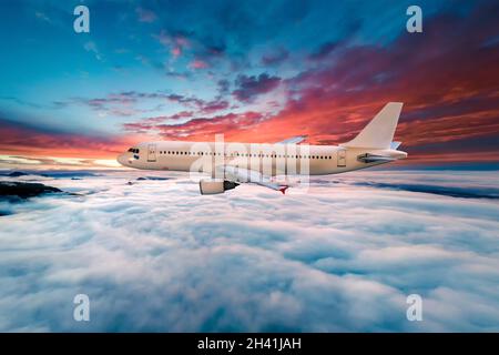 Avion survolant les nuages au coucher du soleil Banque D'Images