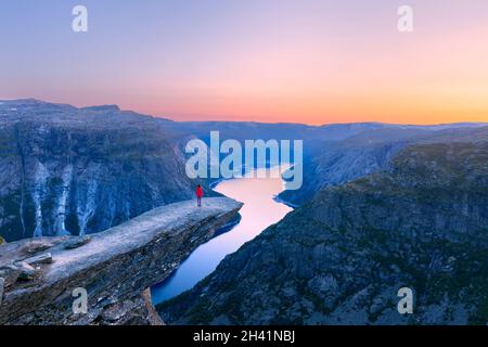 Seul touriste sur le rocher de Trolltunga - la plus spectaculaire et la plus célèbre falaise pittoresque de Norvège - Paysage Banque D'Images