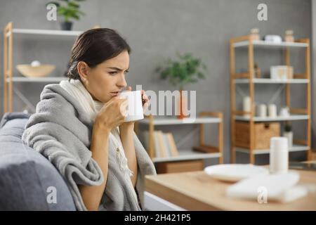 Gros plan de la belle jeune femme malheureuse attrapée par le froid ou la grippe buvant du thé chaud. Banque D'Images